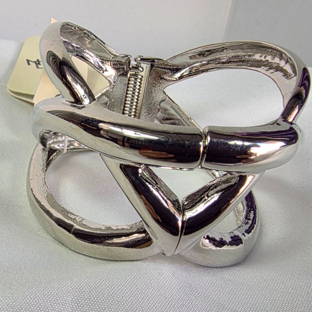 New Directions Silver Tone Knot Bangle Bracelet Featuring an Abstract Design